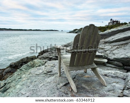 An Adirondack chair sits beside the oceans calm waters before sunset off Castle Hill in Newport,RI.