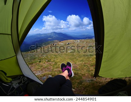Woman lying in tent with a view of mountain and sky in Carpathians mountains, Ukraine,