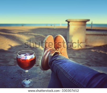 Woman\'s  Feet relaxing on the beach enjoying sun on sunny spring day,wineglass  of sangria . Valencia, Spain