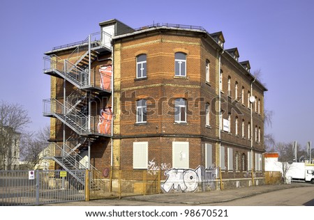 An old brick house with stairs outside and graffiti on a former factory premises in Riesa, East-Germany