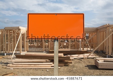 A blank orange construction sign against wood construction site