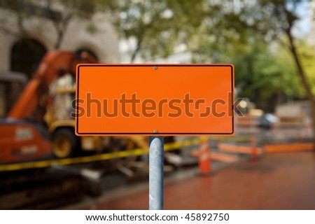 A blank orange construction sign against construction site