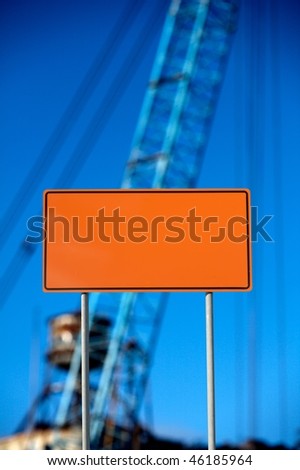 Blank construction sign against construction equipment and clear blue sky