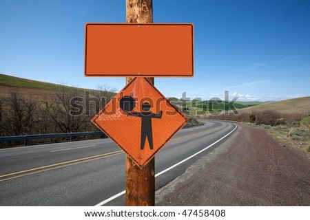 Road construction and flagger sign screwed on wooden pole against winding road