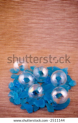 Clear glass bubbles on reed mat with blue rocks.
