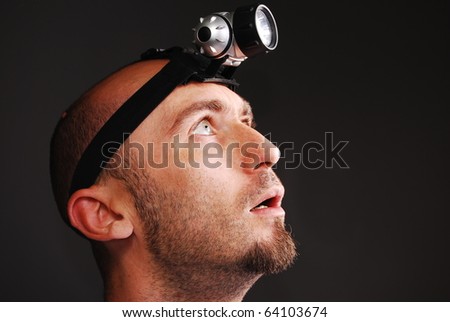 Speleologist with a head lamp on a gray isolated background