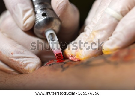 The close-up of a tattooing needle during the tattoo The close-up of a tattooing needle during the tattoo