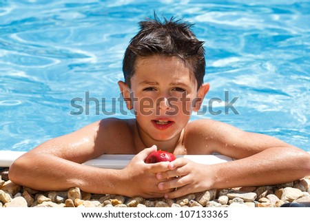 Boy eating fruit in the swimming pool