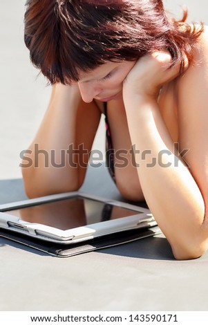 busty woman with swimsuit reading news on tablet outdoor