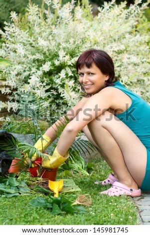 happy smiling middle age woman gardening, offsets the flowers in a pot