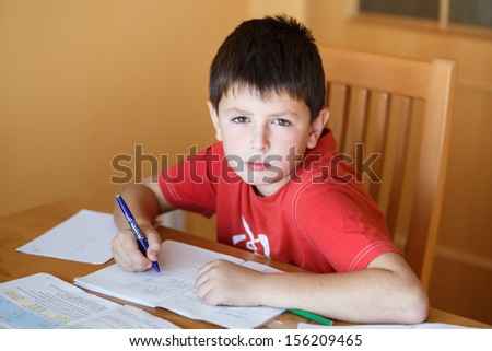 boy doing school homework from mathematics in workbook