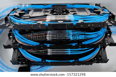 stack of fiber optic splice cassettes with protection sleeve and blue fibres installed in optical distribution frame
