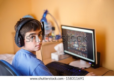 Teenager using computer at home, play game in his child room