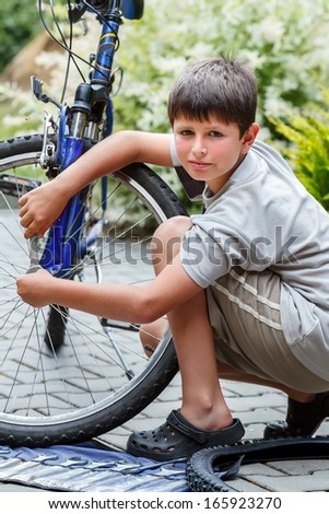 Teenager repairing his bike, using spanner to change broken tyre, outdoor shoot