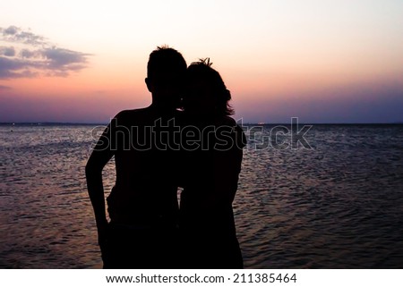 Couple Man and Woman holding hands in Love staying on Beach seaside with sunset scenery. People, Romantic, relationship and Friendship concept.