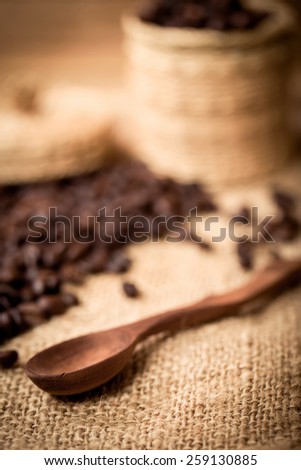 pile of coffee beans and wooden spoon with space for text, focus to spoon with shallow focus