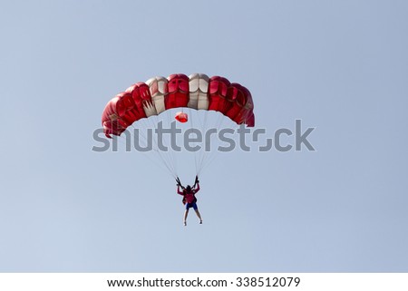 silhouettes of unidentified skydivers parachutist on blue sky on sunset