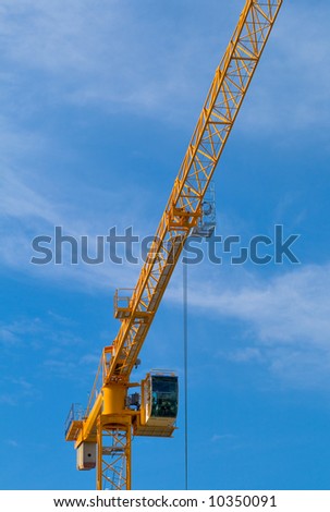 Bright yellow construction crane against clear blue sky.