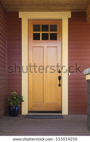 Wooden Front Door Of An Upscale Home. View Of A Wooden Front Door On A Red House With Black Accents. Vertical Shot.
