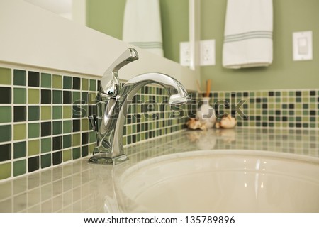 Bathroom sink of an upscale home/Horizontal shot of an elegant, polished and clean sink in an upscale home with colorful green tiling