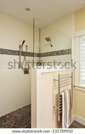 Walk in shower of an upscale home/vertical shot of a large tiled walk in shower of an upscale home with towel on towel rack