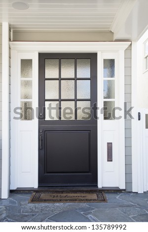 Front Door Of An Upscale Home/Vertical Shot Of A Black Front Door Of An Upscale Home With Reflection In The Frosted Windows And A Welcome Mat