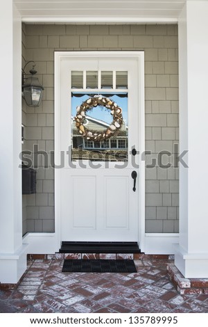 Front door of an upscale home/Vertical shot of a white front door on an upscale home with a wreath, brick, and reflection in the windows