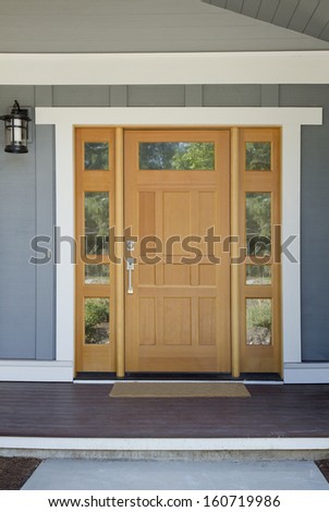 Closed Wooden Front Door Of A Home With Gray Panels In Daytime.