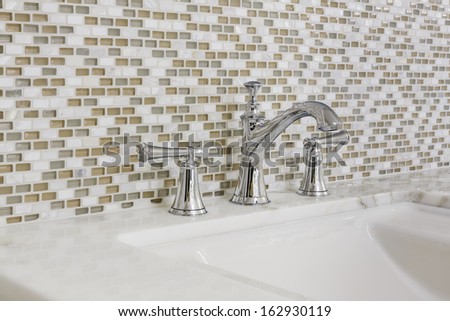 Contemporary Bathroom Sink With Chrome Fixtures, Against A Mosaic Tile Wall.