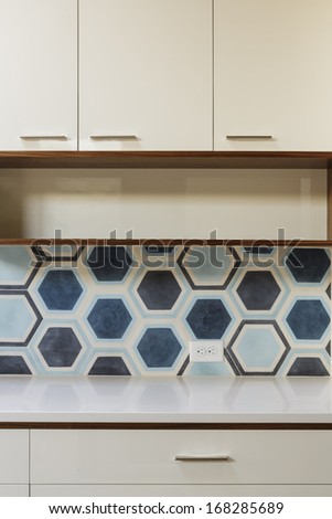 White Kitchen Cabinets With Wood Trim And Hexagonal Blue Tile In Mid-Century Modern Home.