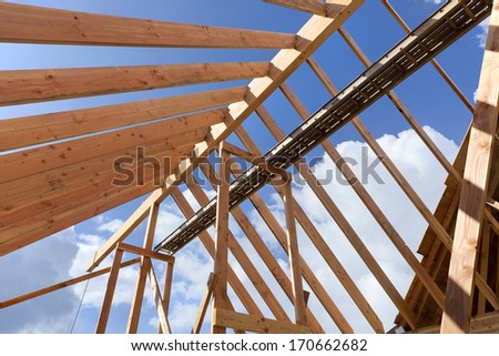 Horizontal shot of post and beam roof construction with view of sky/New Home construction with exposed beams and blue sky background