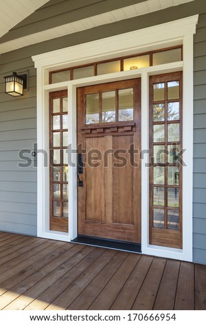 Vertical shot of wooden front door  of an upscale home with windows/Exterior shot of a Wooden Front Door