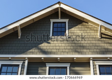 Horizontal shot of an upscale home with blue sky and sun shadows/ Front Roof line of an Upscale Home