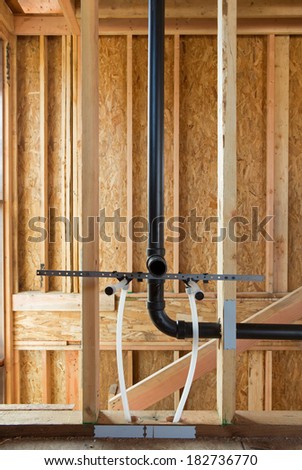 Interior view of New Home construction with exposed plumbing and wood studs.