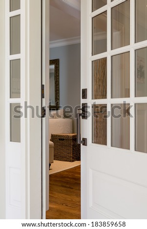 Vertical close-up shot of an open, wooden front door from the exterior of an upscale home with windows.