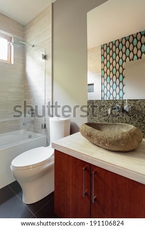Modern bathroom with rock sink fixture/Vertical shot of a model home bathroom