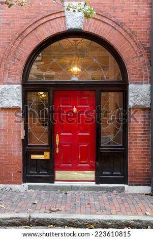 Red Door In Black Archway Door Frame with Windows on Brick Building