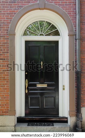 Black Front Door with White Door Frame and Archway Window on a Brick Building
