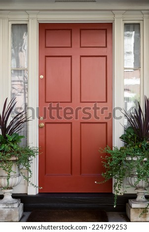 Red Front Door with Surrounding White Door Frame and Windows and Greenery