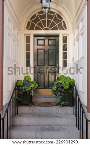 Green Front Door with Lunette and Side Windows in White Panel Arch Entryway with Greenery, Doormat and Overhead Hanging Lamp