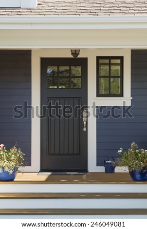Closed Black Front Door with White Surrounding Door Frame and Blue Siding