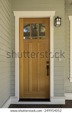 Natural Wood Front Door with Surrounding White Door Frame on Sage Green Exterior