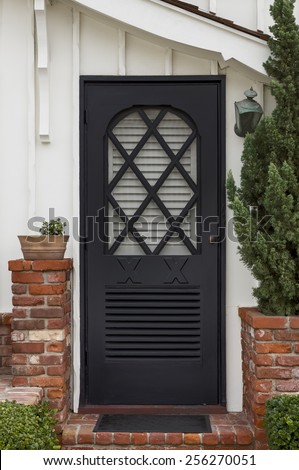 Black Front Door with Diagonal Cross Hatch Window Frame and Short Brick Columns