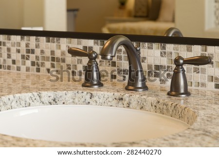 Closeup view of elegant bathroom sink with marble counter top with faucet in focus.