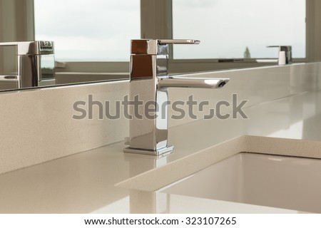 Chrome water faucet with marble counter tops and a white sink