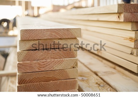 Selective focus image of stacks of lumber sitting at a construction site of a new home. Horizontal shot.