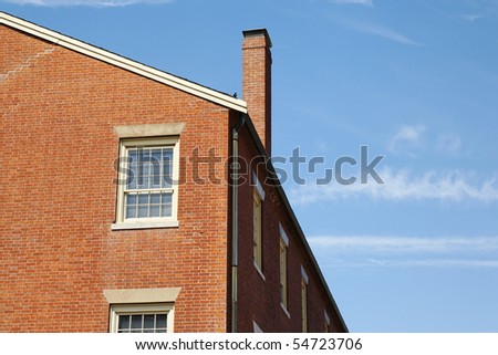 Low angle view of a brick building against a clear blue sky. A chimney is jutting out of the roof. Horizontal shot.