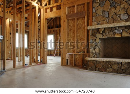 Interior view of a new home under construction. A stone fireplace has been installed. Horizontal shot.