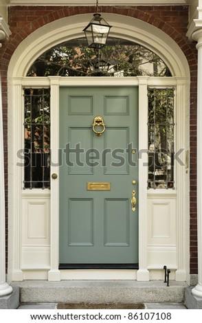 Front entrance to a home with classic design. The door has a large brass knocker and an elegant frame. Vertical shot.