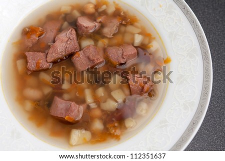 Hot Bowl of meaty bouillon soup with chunks of meat and vegetables in broth